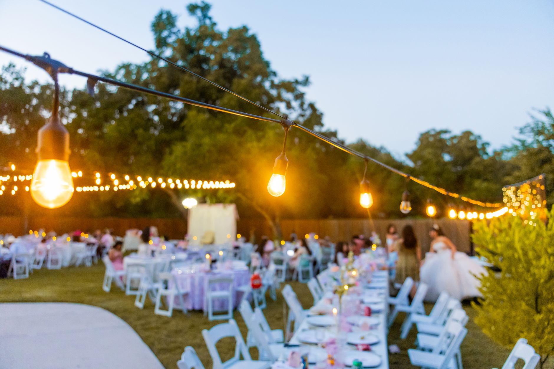 Reception dinner table set outdoors under string lights